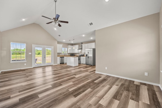 unfurnished living room with french doors, ceiling fan, high vaulted ceiling, and light wood-type flooring