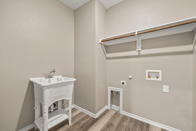 clothes washing area with hookup for a washing machine, hookup for an electric dryer, and light wood-type flooring