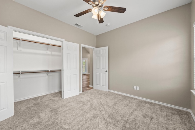 unfurnished bedroom with light colored carpet, a closet, and ceiling fan