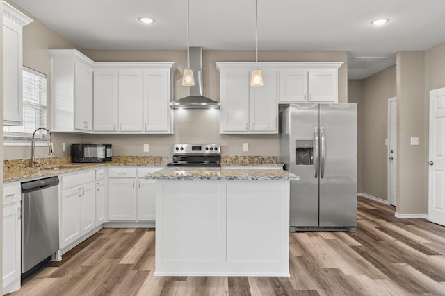kitchen with light wood finished floors, appliances with stainless steel finishes, wall chimney range hood, and a sink