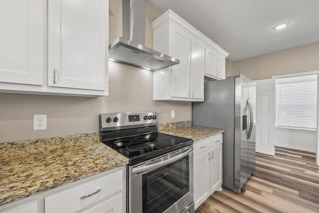 kitchen with light stone countertops, white cabinetry, appliances with stainless steel finishes, and wall chimney exhaust hood