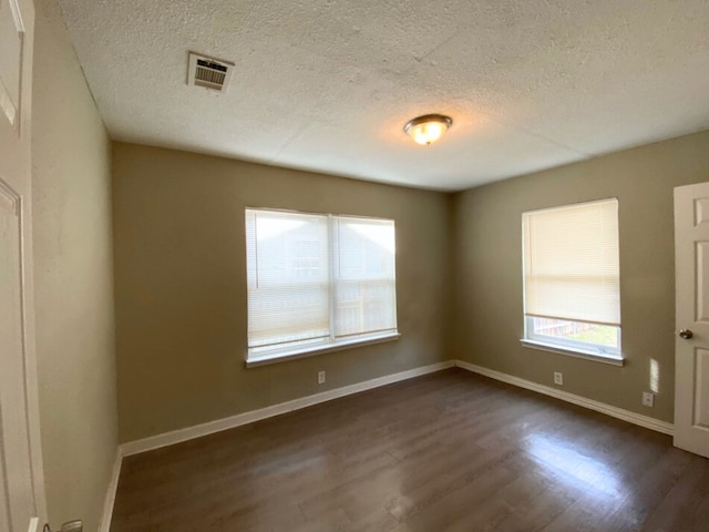 spare room with dark hardwood / wood-style flooring and a textured ceiling