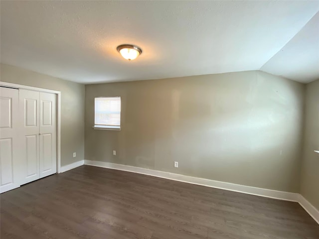 unfurnished bedroom with a closet, vaulted ceiling, and dark hardwood / wood-style floors