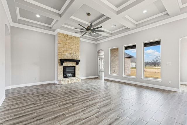 unfurnished living room featuring coffered ceiling, ceiling fan, a fireplace, beamed ceiling, and light hardwood / wood-style floors