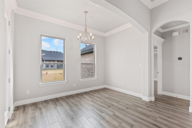 spare room with an inviting chandelier, ornamental molding, and light hardwood / wood-style flooring