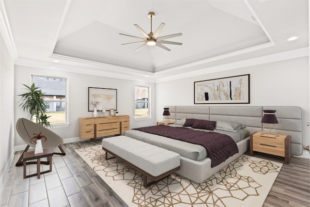 bedroom with hardwood / wood-style flooring, ceiling fan, crown molding, and a tray ceiling