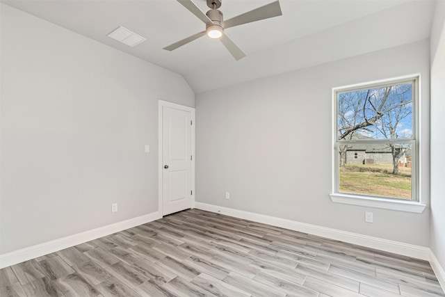 spare room featuring light wood-type flooring, vaulted ceiling, a wealth of natural light, and ceiling fan