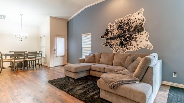 living room featuring high vaulted ceiling, an inviting chandelier, wood-type flooring, and ornamental molding