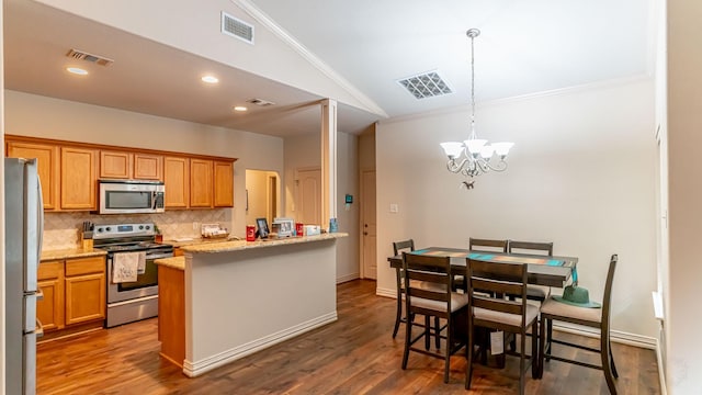 kitchen featuring an inviting chandelier, vaulted ceiling, appliances with stainless steel finishes, decorative light fixtures, and dark hardwood / wood-style flooring