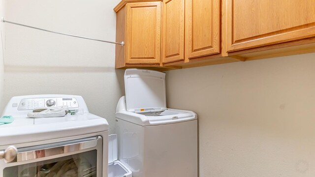 laundry area with washer and dryer and cabinets