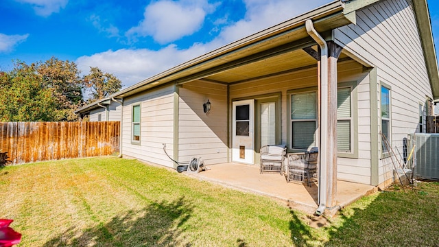 rear view of house featuring central AC, a lawn, and a patio area