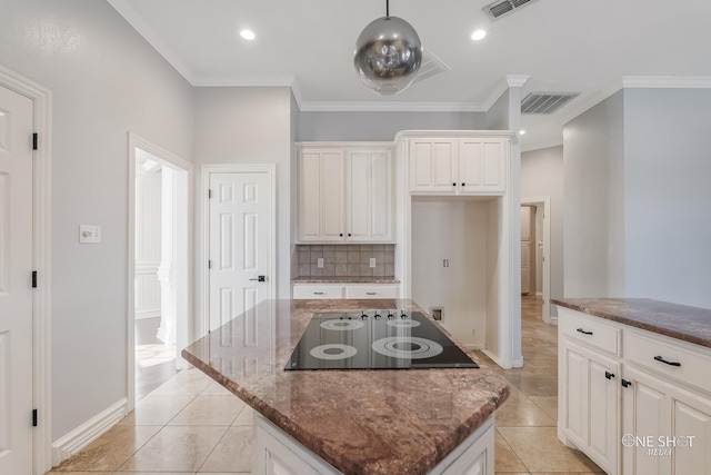 kitchen with dark stone countertops, a center island, black electric stovetop, ornamental molding, and decorative backsplash