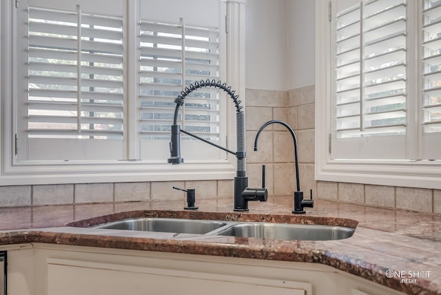 interior details featuring tasteful backsplash, sink, white cabinets, and stone counters