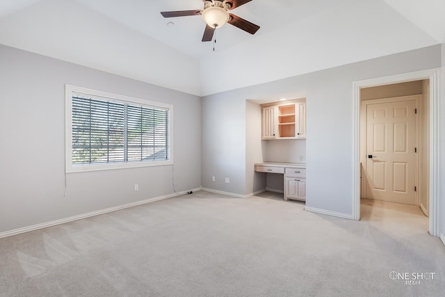 unfurnished bedroom featuring lofted ceiling, built in desk, and light carpet