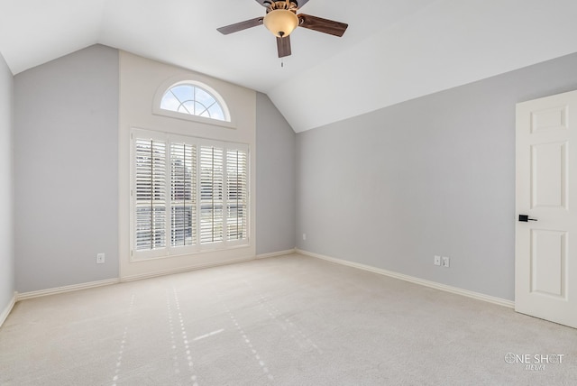 spare room with ceiling fan, light colored carpet, and vaulted ceiling