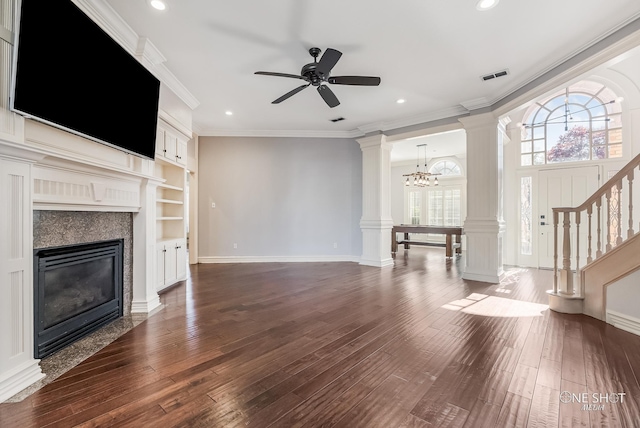 unfurnished living room with decorative columns, a fireplace, ornamental molding, dark hardwood / wood-style flooring, and ceiling fan with notable chandelier