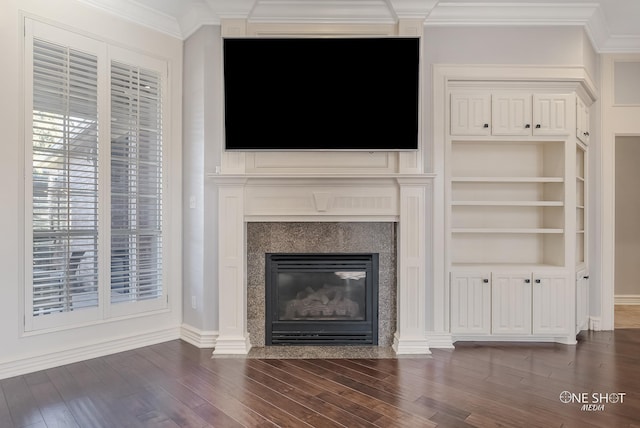 unfurnished living room featuring crown molding, a high end fireplace, dark hardwood / wood-style floors, and built in shelves