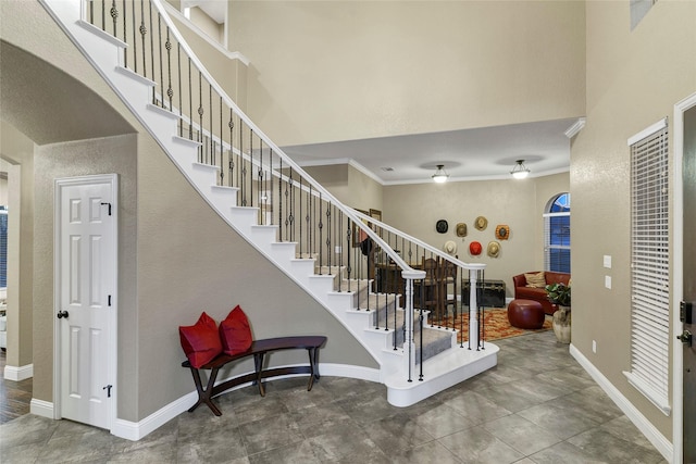 staircase featuring a high ceiling and crown molding