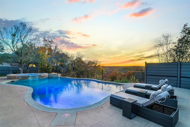 pool at dusk with an in ground hot tub and a patio area