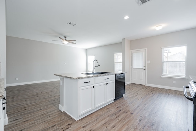 kitchen featuring plenty of natural light, sink, black dishwasher, and a kitchen island with sink