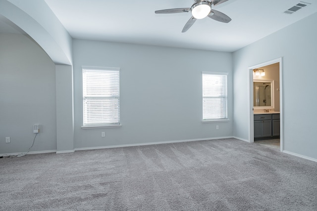 unfurnished bedroom featuring ensuite bath, ceiling fan, and light carpet