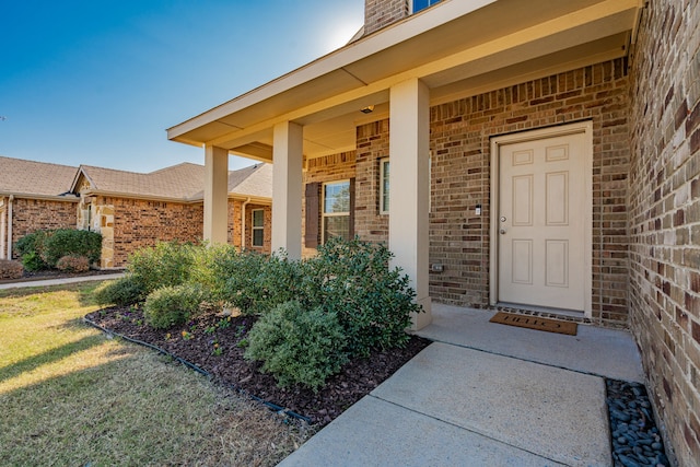 view of exterior entry with a porch and a yard