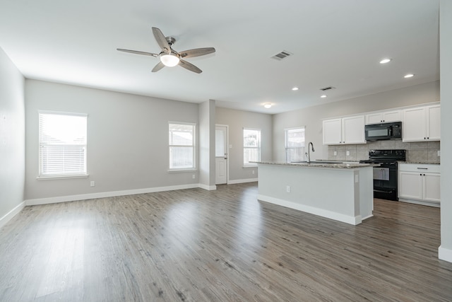 kitchen with a kitchen island with sink, backsplash, hardwood / wood-style floors, black appliances, and white cabinets