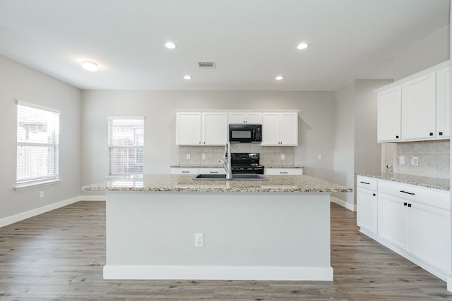 kitchen with white cabinets, an island with sink, and black appliances