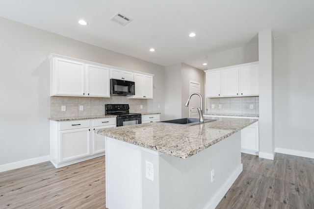 kitchen featuring a kitchen island with sink, sink, white cabinets, and black appliances