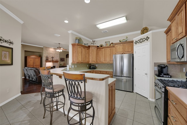 kitchen featuring a breakfast bar, appliances with stainless steel finishes, kitchen peninsula, and ornamental molding