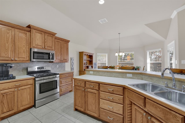 kitchen with sink, backsplash, a chandelier, lofted ceiling, and appliances with stainless steel finishes