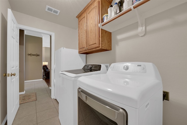 laundry area featuring cabinets, independent washer and dryer, and light tile patterned floors