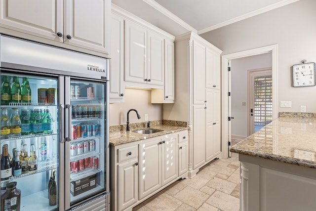 kitchen with stainless steel refrigerator, light stone countertops, sink, crown molding, and white cabinets