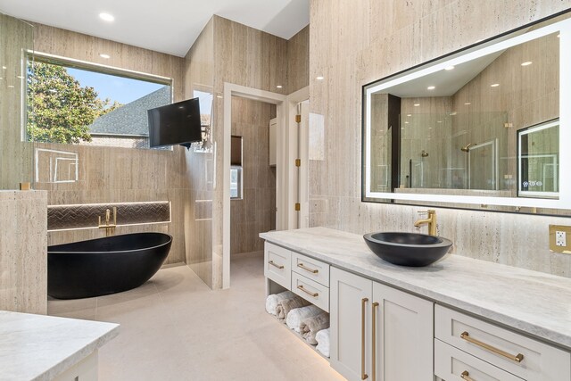 bathroom with shower with separate bathtub, vanity, and tile walls