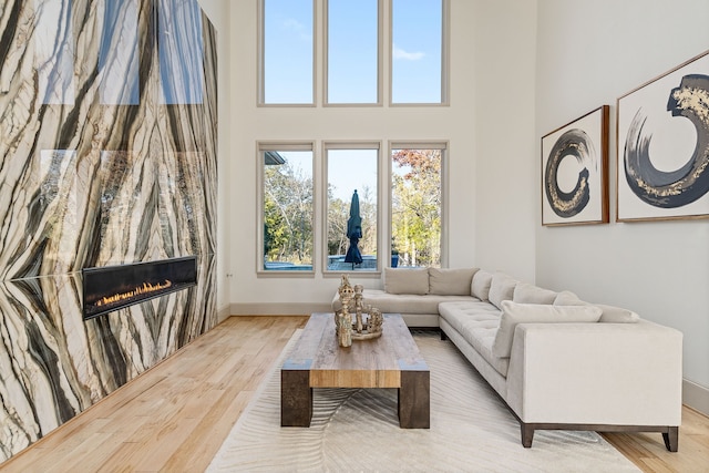 living room with light wood-type flooring and a towering ceiling