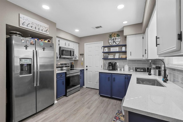 kitchen featuring blue cabinets, white cabinets, appliances with stainless steel finishes, and sink