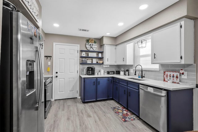 kitchen with light hardwood / wood-style floors, stainless steel appliances, blue cabinetry, white cabinets, and sink