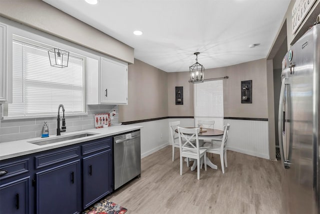 kitchen with pendant lighting, blue cabinets, white cabinets, appliances with stainless steel finishes, and sink