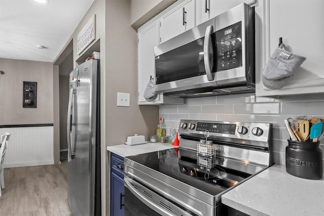 kitchen featuring light hardwood / wood-style floors, stainless steel appliances, blue cabinetry, white cabinetry, and backsplash