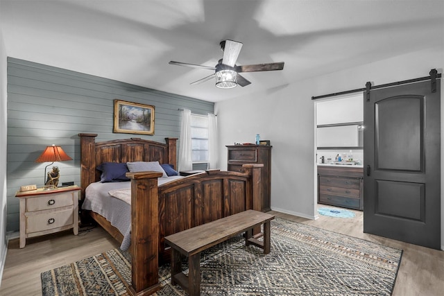 bedroom with ceiling fan, light hardwood / wood-style floors, and wood walls