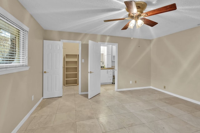 unfurnished bedroom with a spacious closet, light tile patterned floors, ceiling fan, a textured ceiling, and a closet