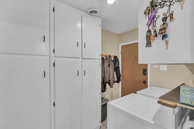 washroom with independent washer and dryer, cabinets, and a textured ceiling