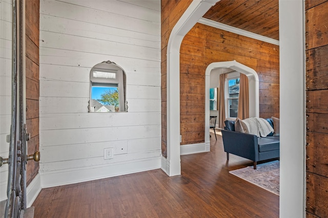 interior space with dark hardwood / wood-style flooring, a healthy amount of sunlight, crown molding, wooden ceiling, and wood walls