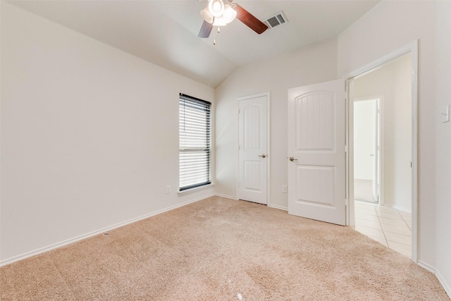 unfurnished bedroom featuring vaulted ceiling, light colored carpet, and ceiling fan