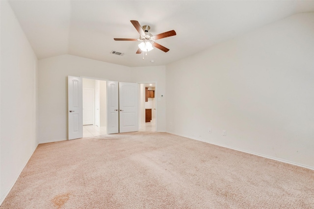 spare room with light carpet, vaulted ceiling, and ceiling fan