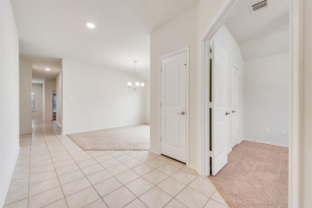 hallway featuring light carpet and a chandelier