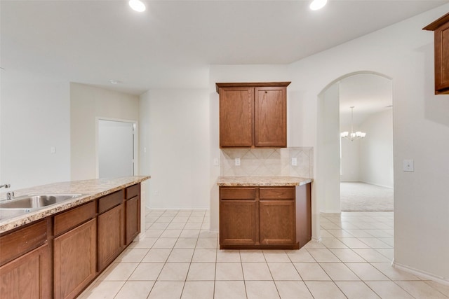 kitchen with light tile patterned flooring, light stone countertops, sink, and backsplash