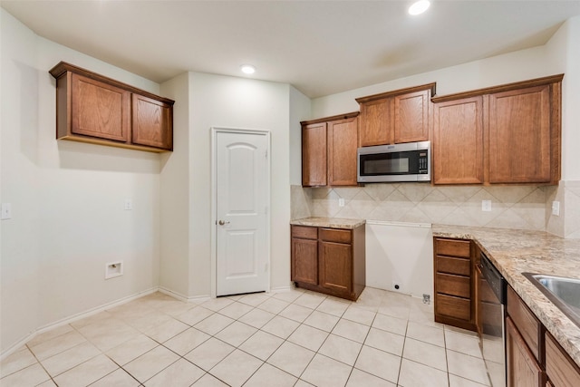 kitchen featuring light tile patterned flooring, built in desk, tasteful backsplash, light stone counters, and stainless steel appliances