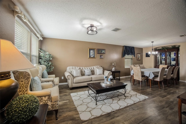 living room with dark wood-type flooring, a textured ceiling, and a notable chandelier