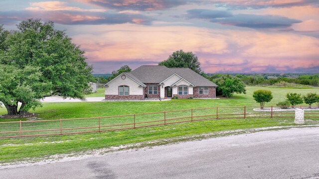 view of front of home with a yard and a rural view